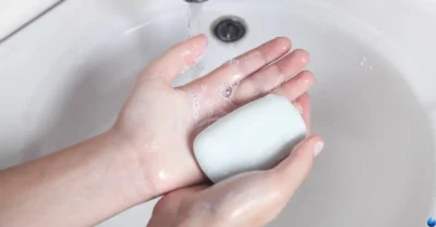 iemand wast zijn handen onder de kraan met een blok handzeep